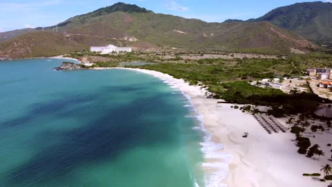 Beautiful beach with a clear blue ocean and a white house in the distance Видео 292393026