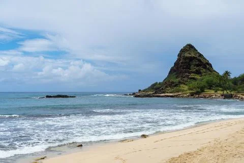 Beautiful beach, mountain backdrop, waves crashing on sandy shore Stock Photos