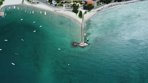 Beautiful beach next to a small tropical town with a long pier on it. Stock Footage 157387635