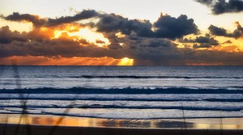 Beautiful Beach Sunset Behind Clouds over ocean horizon Landscape Stock Photos