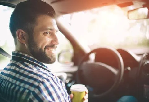 Beautiful bearded man smiling while sitting on the front passenger seats in t Stock-Fotos