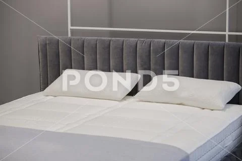 A beautiful bed unshaded with bed linens for advertising mattresses and pillo Stock Photos