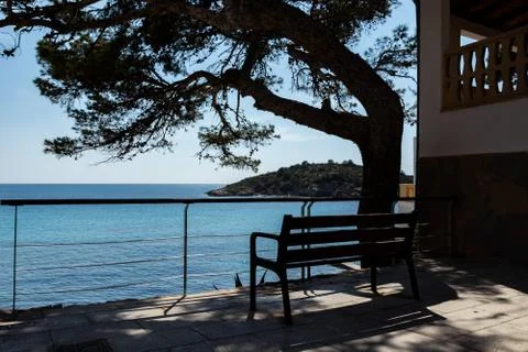 Beautiful bench under a big tree with view to the coastline of sant elm 스톡 사진