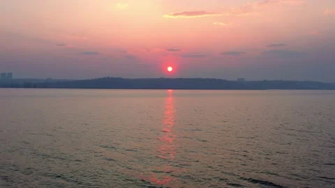 A beautiful big sun sets outside the city on a hill near the lake. 스톡 동영상 221695596