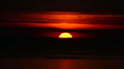 A beautiful big sun sets over the horizon of a seaside city at sunset Stock Footage 339032663