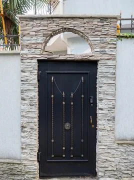 Beautiful black gate with forging elements in an arched stone opening Foto stock