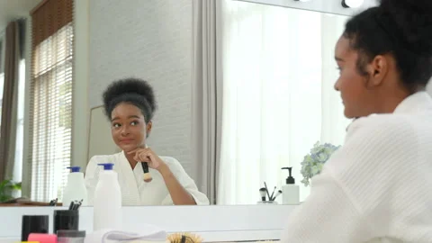Beautiful black teenage girl using blusher to apply makeup Stock Footage 309902853