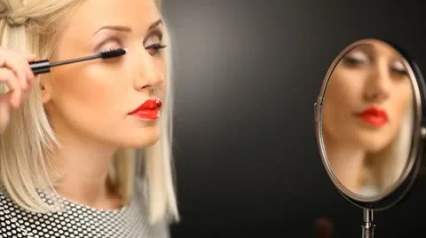 Beautiful blond model applying mascara on her eyelashes in the mirror Stock Footage 10583840