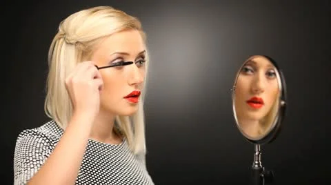 Beautiful blond model applying mascara on her eyelashes in the mirror Stock-Footage 10583855