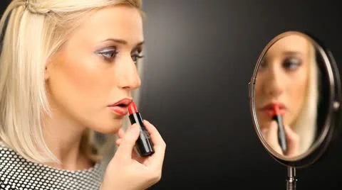 Beautiful blond model applying red lipstick in the mirror Stock Footage 10583850