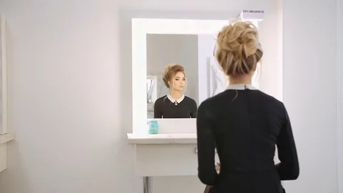 Beautiful blond model looking into the mirror in the beauty salon Stock Footage 74459588