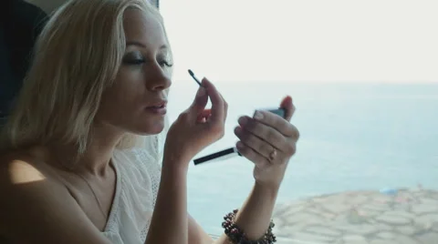 Beautiful blonde applying eye shadow and lip gloss Stock Footage 59804434
