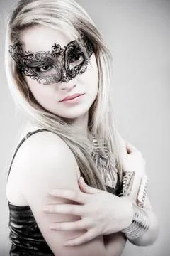 Beautiful blonde in black leather jacket, mysterious mask and silver jewelry Stock Photos