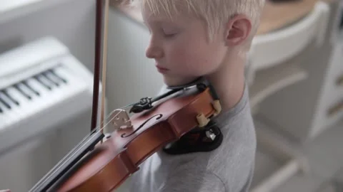 A beautiful blonde boy learns to play the violin in a music school. Stock Footage 145459902