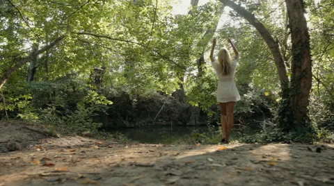 Beautiful blonde clothed in a dress resting by the pond in the forest Stock Footage 59321446