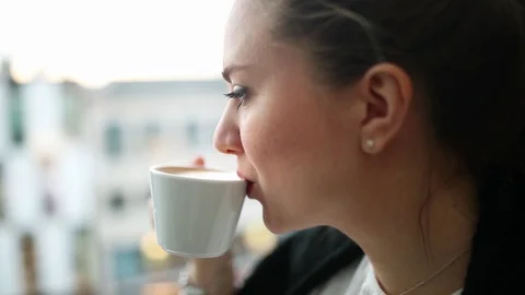Beautiful blonde drinks coffee in a cafe and looks into the distance Stock Footage 128387752