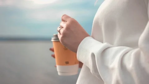 A beautiful blonde drinks coffee while walking along Stockbeeldmateriaal 162196323
