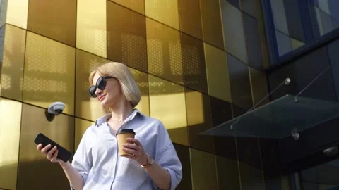 A beautiful blonde with glasses smiling while browsing phone during coffee break Stock Footage 168798883