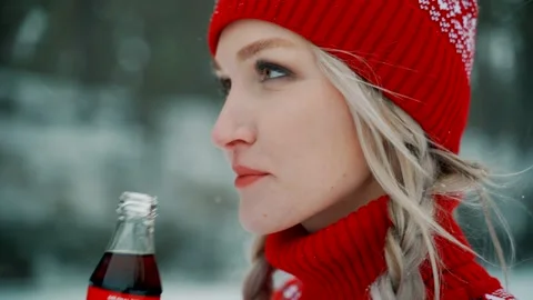 A beautiful blonde in a red cap drinks a cola from a glass bottle. Stock Footage 145114460