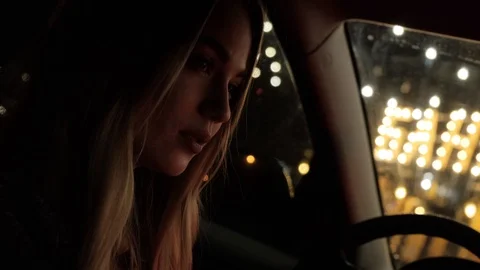 A beautiful blonde is sitting in a car. Night city. The girl with a sad look. Stock Footage 126242596