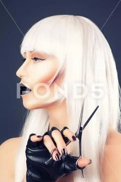Beautiful blonde woman with black make-up and accessories posing with scissor Stock Photos