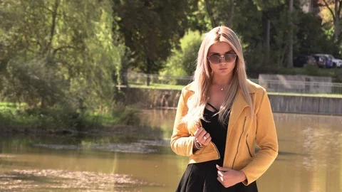 Beautiful blonde in a yellow jacket and sunglasses Stock Footage 116476850