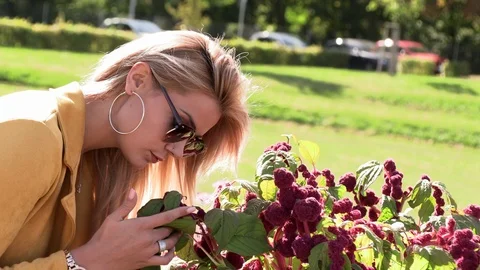 Beautiful blonde in a yellow jacket sniffs flowers Stock Footage 116593213