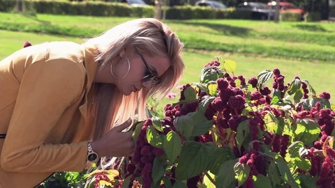 Beautiful blonde in a yellow jacket sniffs flowers Stock Footage 116607843