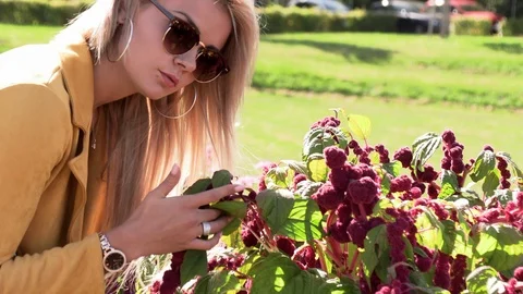 Beautiful blonde in a yellow jacket sniffs flowers Stock Footage 117570366