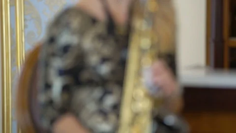 Beautiful blonde young woman is playing the saxophone. Sexy girl in golden black Stock Footage
