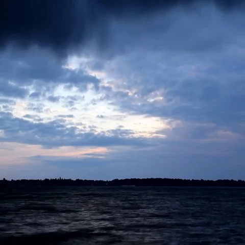 Beautiful blue clouds move fast over water at dawn Video stock 69563020