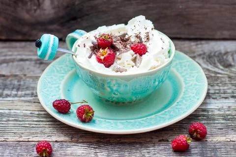 A beautiful blue cup of coffee with whipped cream, cocoa powder and raspber.. Stock Photos