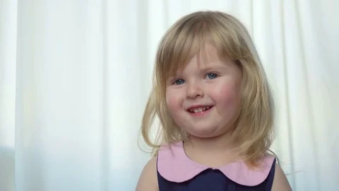 Beautiful blue-eyed girl leans her head and smiles Stock Footage