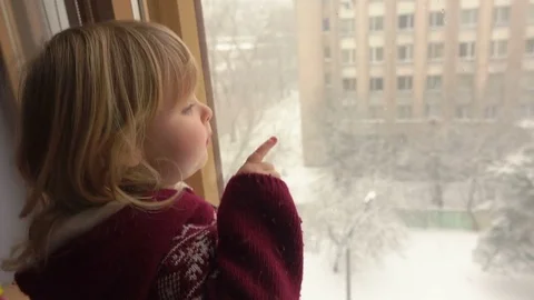 Beautiful blue-eyed girl looks through the window Stock Footage