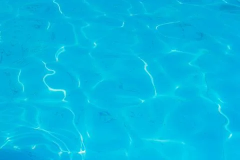 Beautiful blue ripple water surface in swimming pool with sun reflection Stock Photos