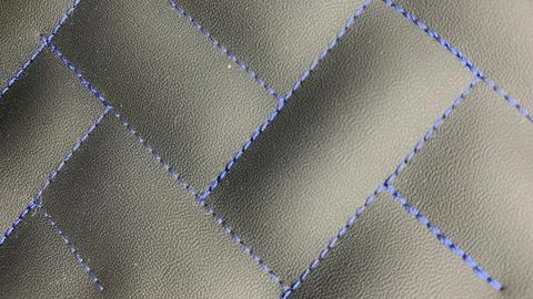 Beautiful blue thread stitching on the black leather. Stock Photos