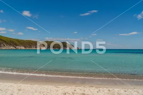 Beautiful blue water bay, empty beach, crystal clean water, blue sky on sunny Stock Photos