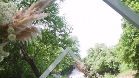 Beautiful boho tipi arch decoration on outdoor wedding ceremony nearby waterfall Stock Footage 252081156