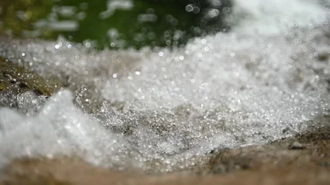 Beautiful bokeh of water running into a pool in the mountains (slow motion) Video stock 219635954