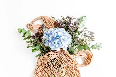 Beautiful bouquet of hydrangeas in a string, eco bag on white background. Flat Stock Photos