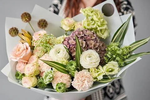 Beautiful bouquet of mixed flowers in womans hands. the work of the florist at a Stock Photos