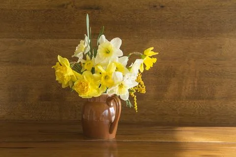 Beautiful bouquet of yellow jonquil or daffodils in vase on a wooden backgr.. Stock Photos