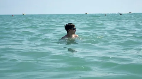 Beautiful boy and the sea. Boy teen swims in the ocean sea. Summer vacation on Stock Footage