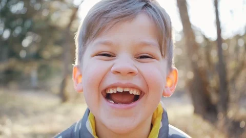 Beautiful boy laughing looking into camera. Cute funny child outdoors portrait Stock Footage 126936389