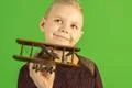 The beautiful boy play with a wooden plane on the green background Photo