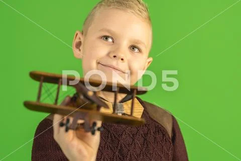 The beautiful boy play with a wooden plane on the green background Stock Photos