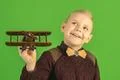 The beautiful boy play with a wooden plane on the green background Photo