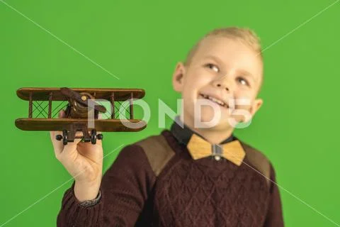 The beautiful boy play with a wooden plane on the green background Stock Photos