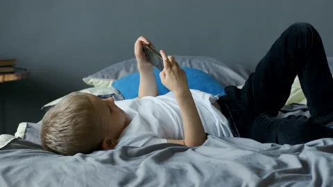 Beautiful boy playing mobile game on smartphone at home. Teenager playing mobile Stock Footage 156244926