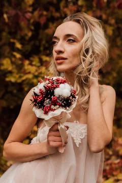 Beautiful bride with a bouquet in her hands. Wedding in autumn in the forest Stock Photos